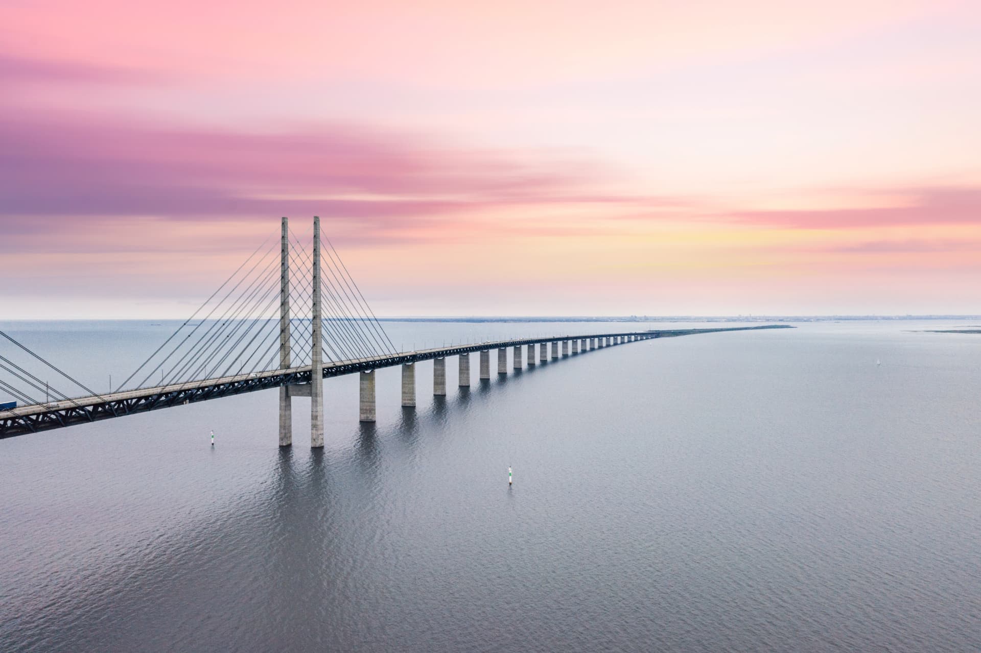 Long cable-stayed bridge stretching across calm water at dusk