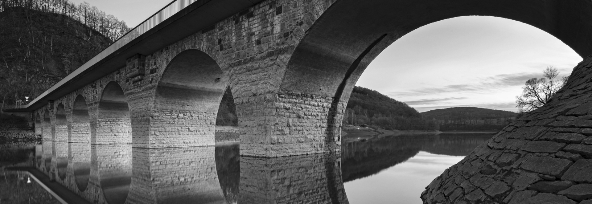 Stone arch bridge reflecting on calm water