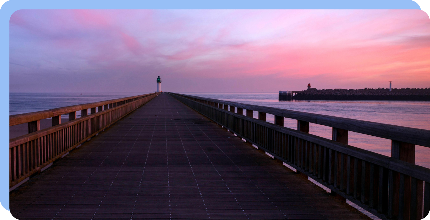 Wooden pier leading to a lighthouse at sunset